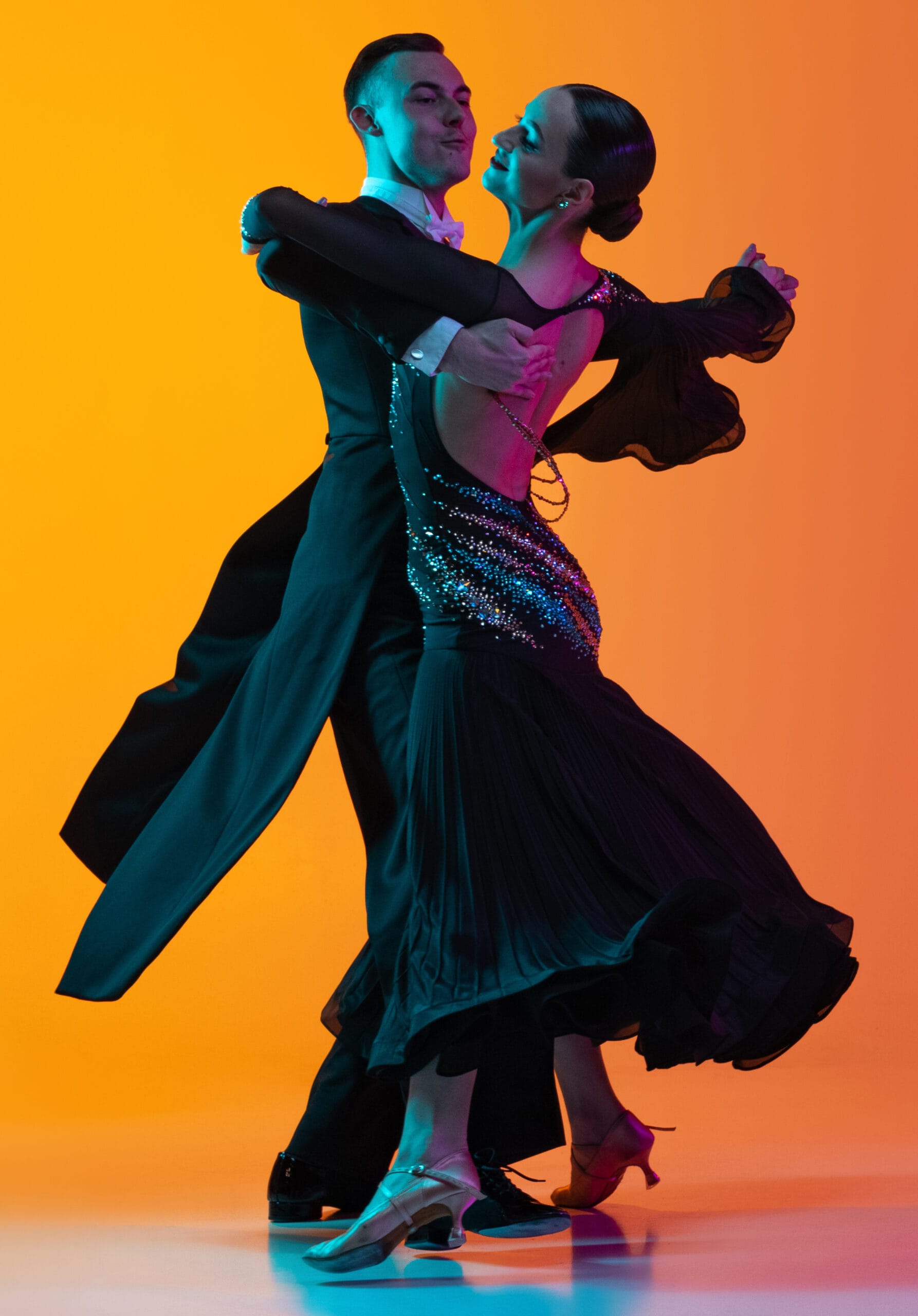 Flyer with dancing couple, beautiful man and woman dancing waltz isolated over gradient orange pink background in neon light. beauty, art, sport concept
